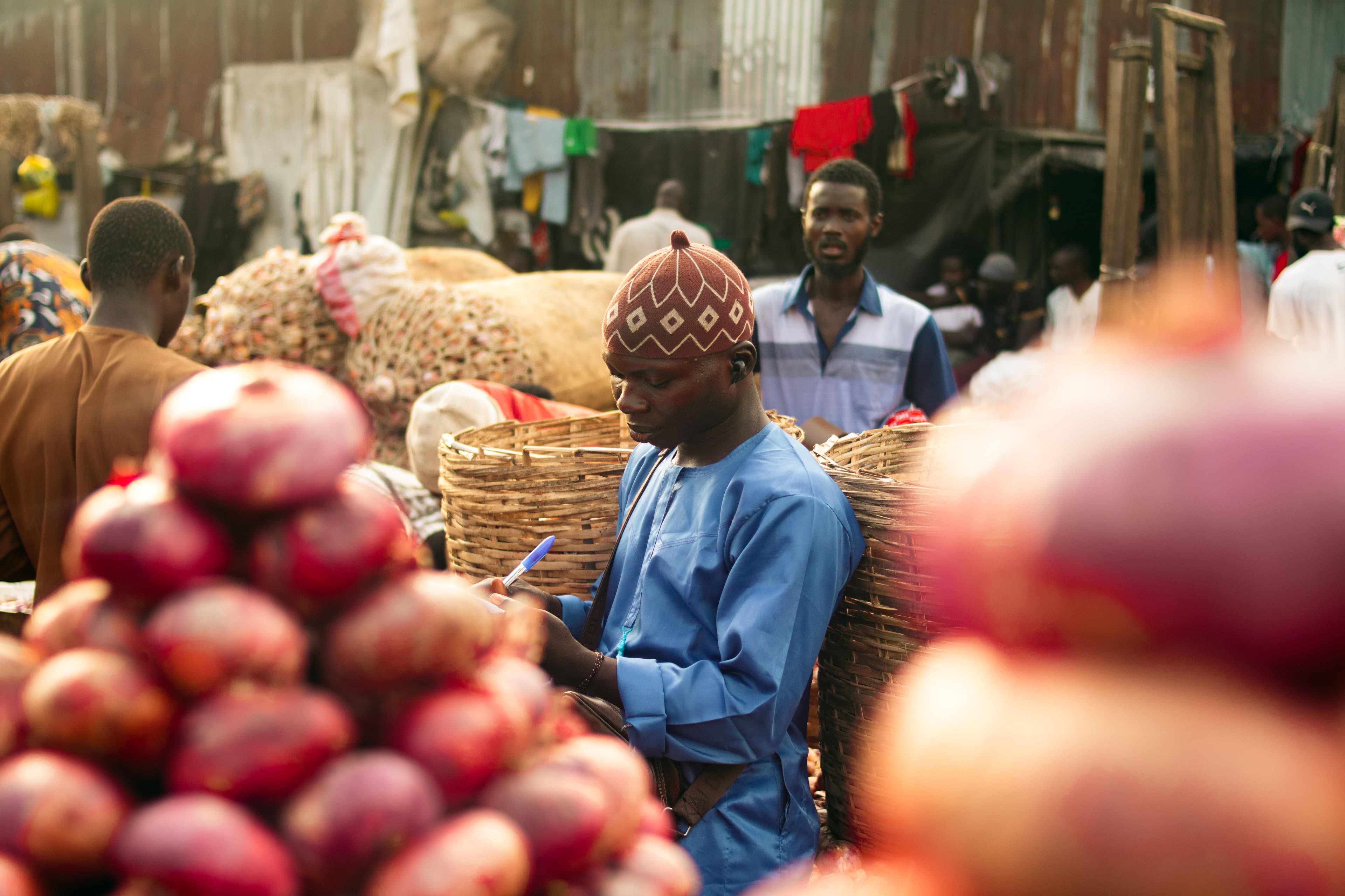 A trader noting an order beside baskets of red onions at a Lagos mainland market.